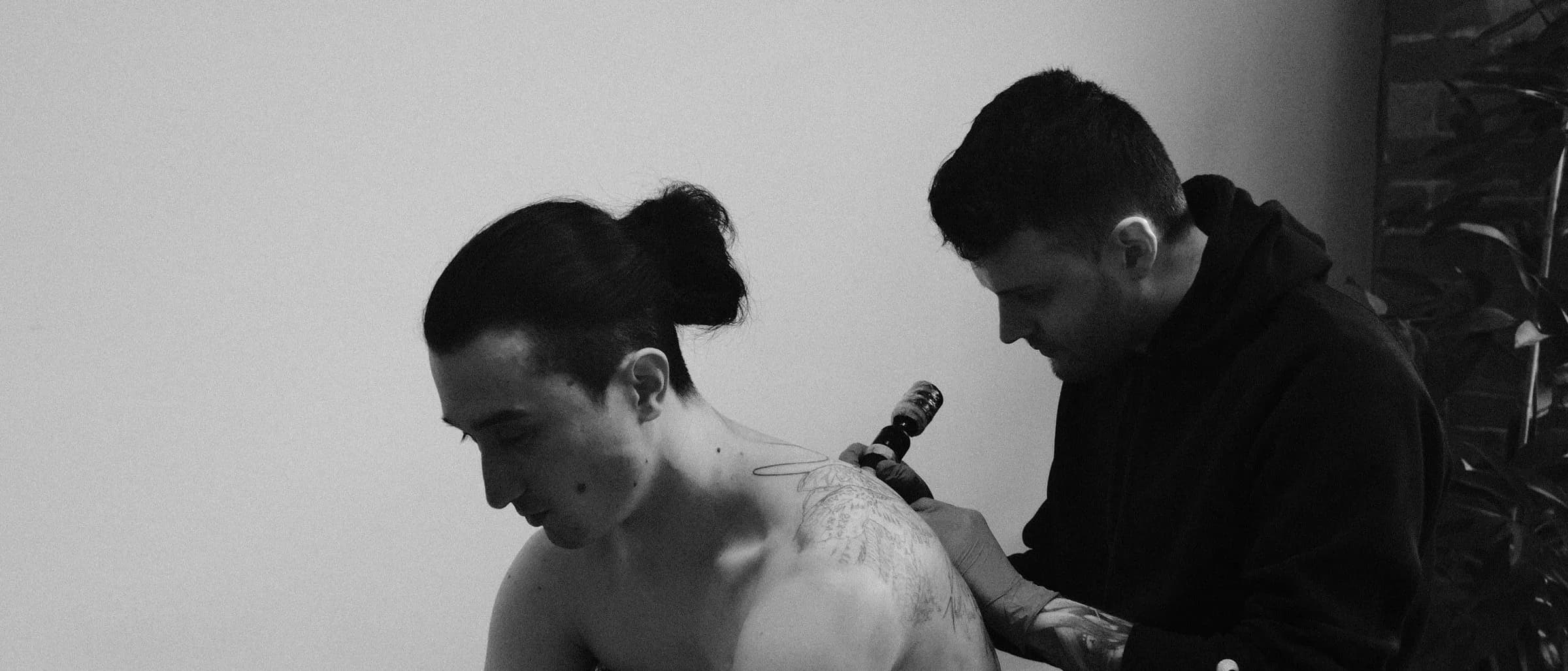 Dom Carter tattooing a client's shoulder at Seventh Day Studio.