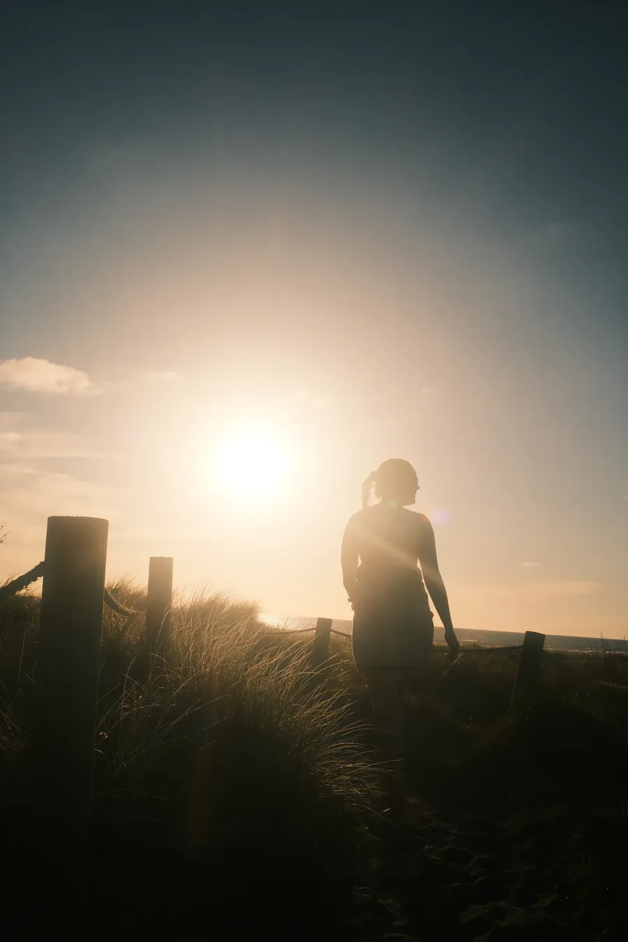 A figure on a dune, backlit by a low sun.