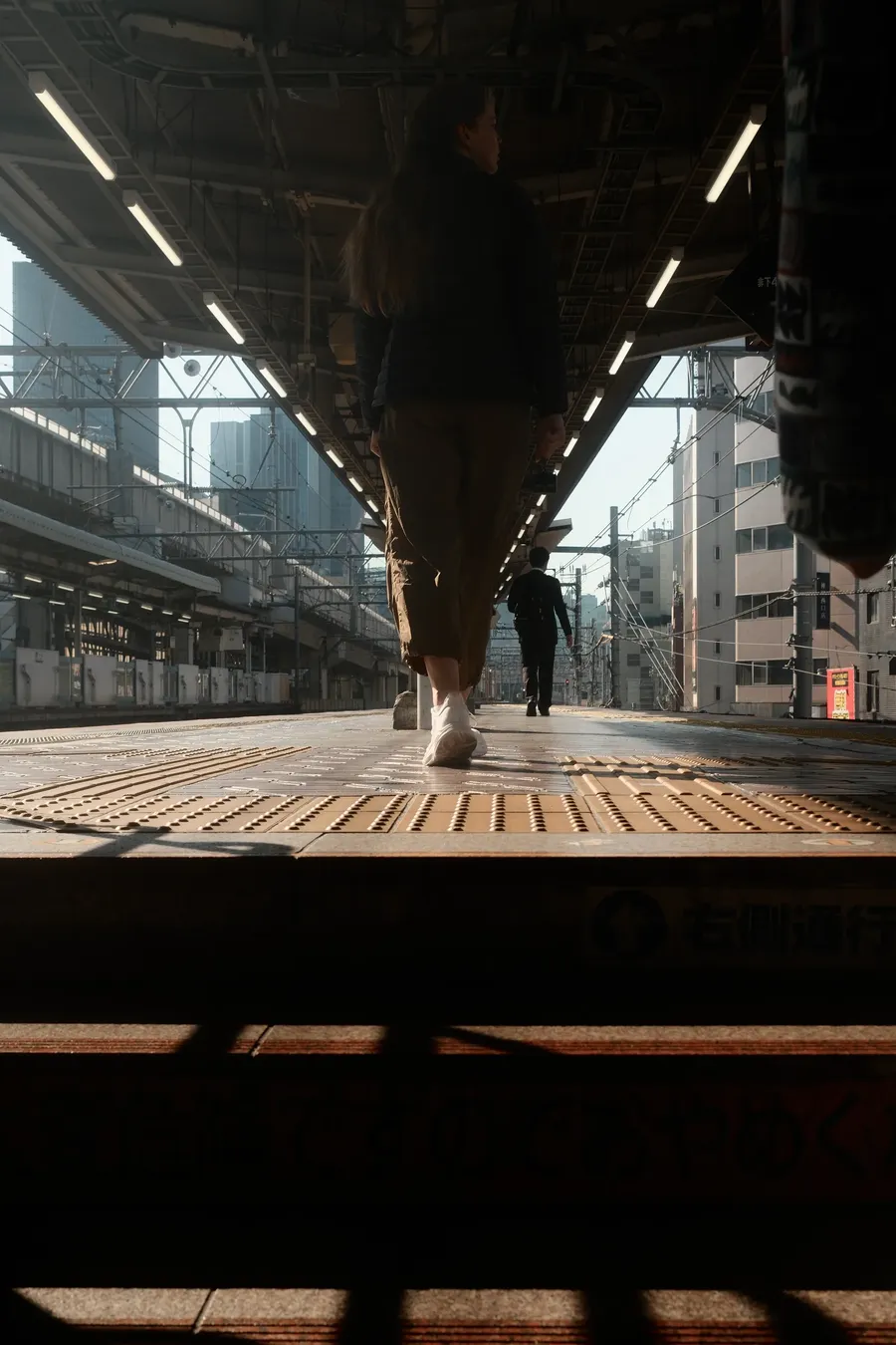 A figure walking under a bridge.