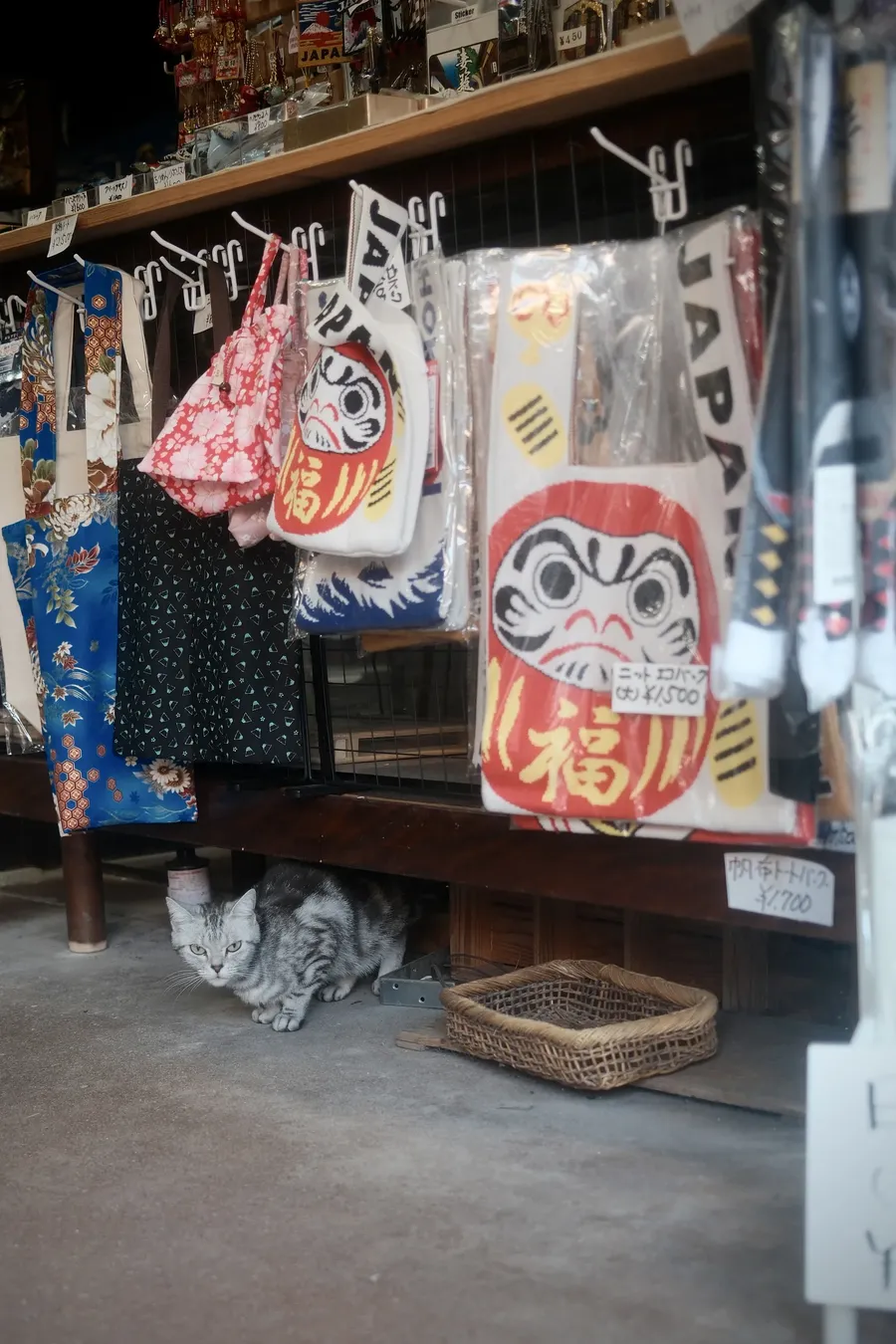 Painted daruma and cloth bags hanging at a shop front.