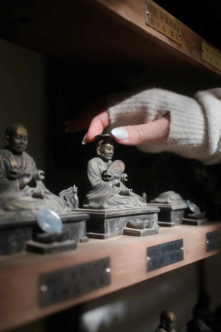 A hand reaching for small figures on a shelf.
