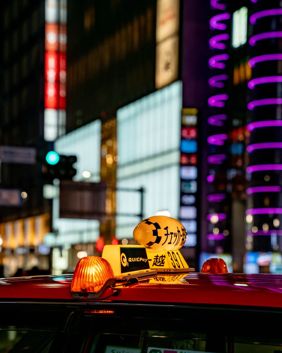 A taxi roof light against a street of neon.